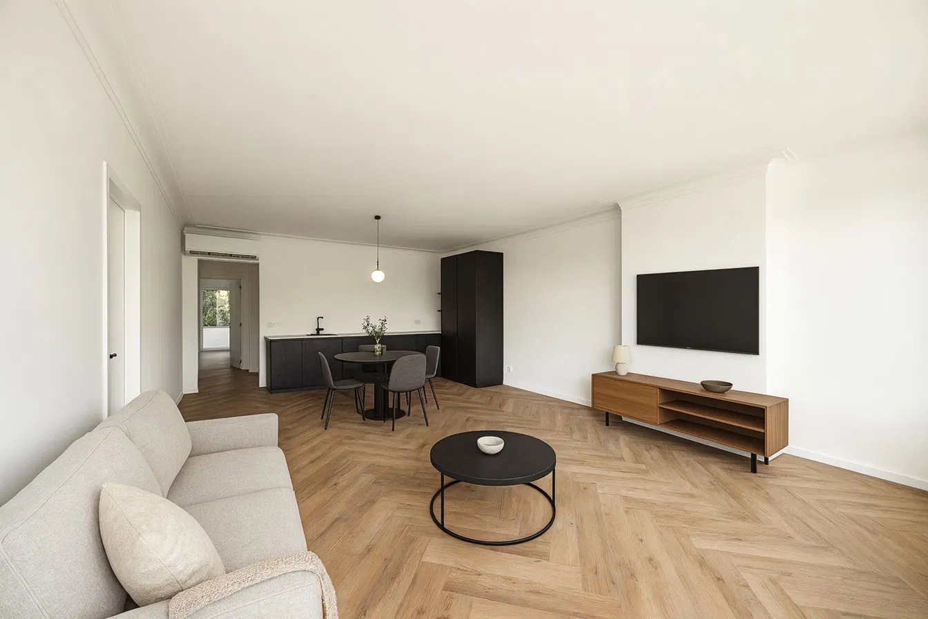 Ingerichte leefruimte met zithoek, ronde eettafel en zwarte keuken op visgraatparket in Residentie Den Berm in Mortsel