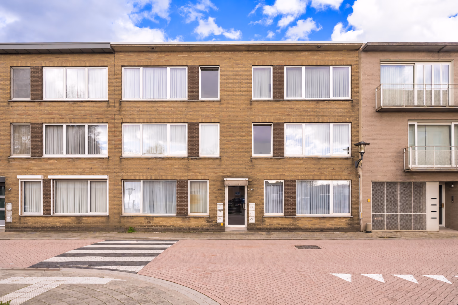 Voorgevel van appartementsgebouw Welkomstraat 47 in Wommelgem, een gele bakstenen gevel met drie bouwlagen